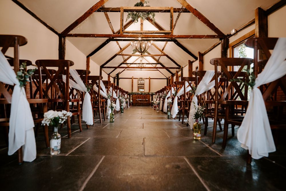 Interior view of a barn wedding venue with exposed wooden beams and elegant white draping.