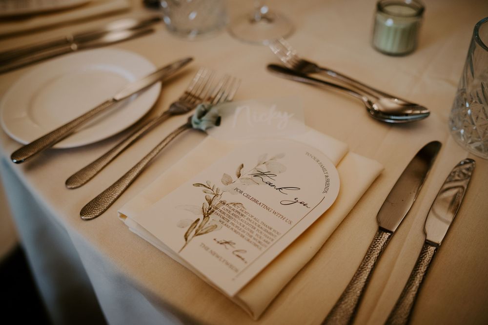 Elegant place settings featuring silverware and printed menus arranged on a table at an upscale restaurant.