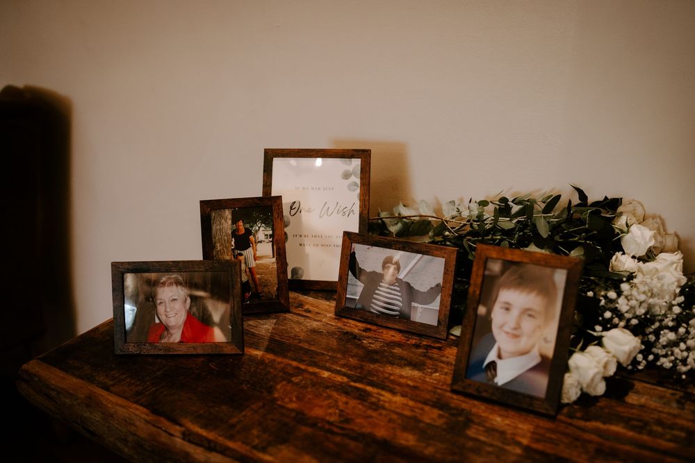 Collection of framed photographs and decorative items displayed on rustic wooden furniture surfaces.
