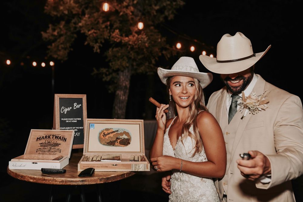 a bride and groom and their guests laughing and sharing cigars at Whispering Oaks barn reception