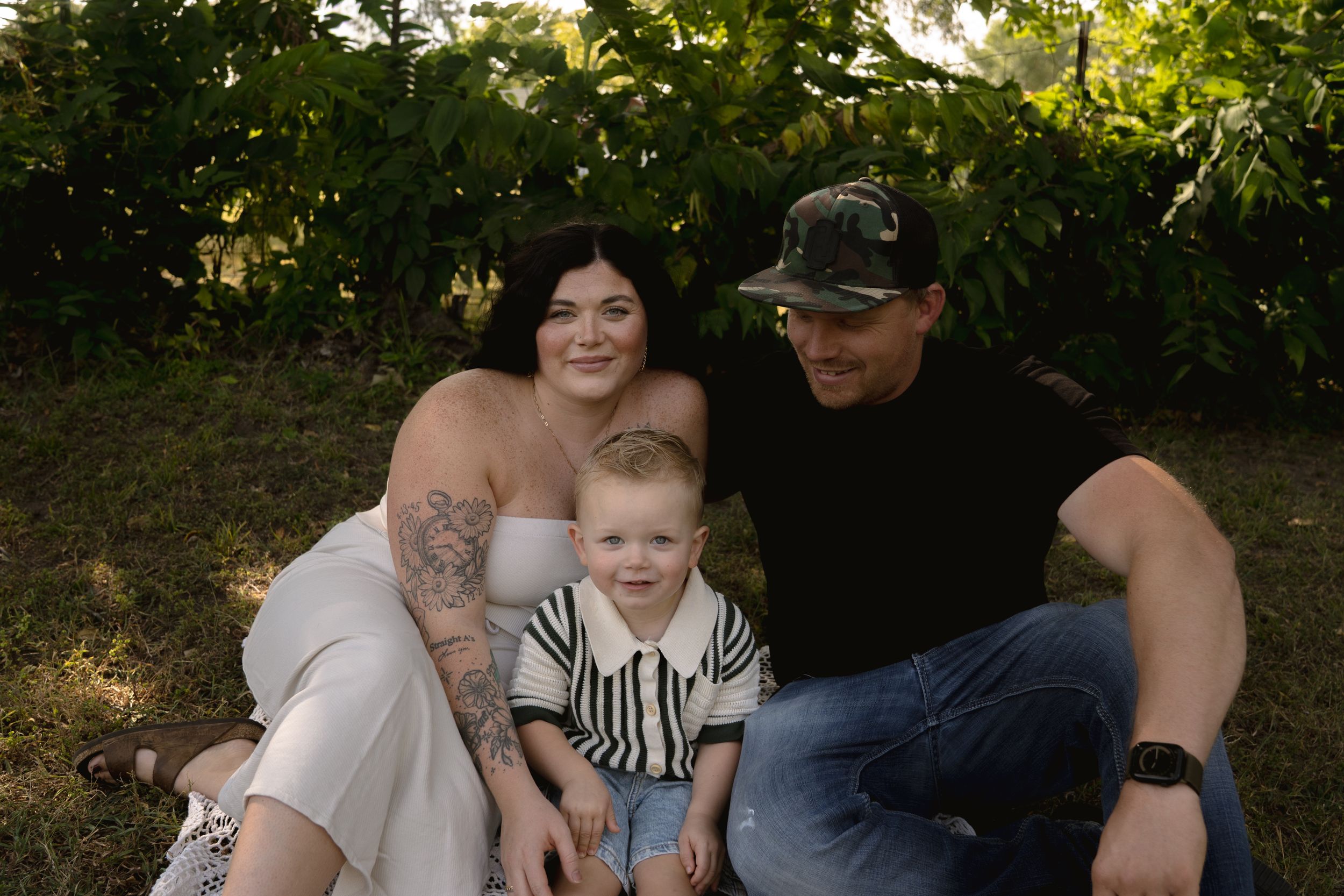 Family portrait session outdoors with lush greenery and natural lighting.