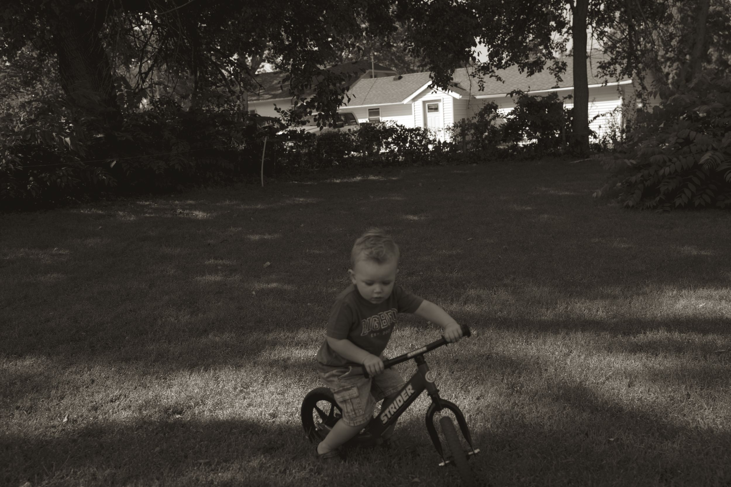 Black and white photo of children playing in a shaded backyard setting.