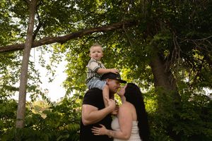A loving family moment captured in golden sunlight beneath towering trees.