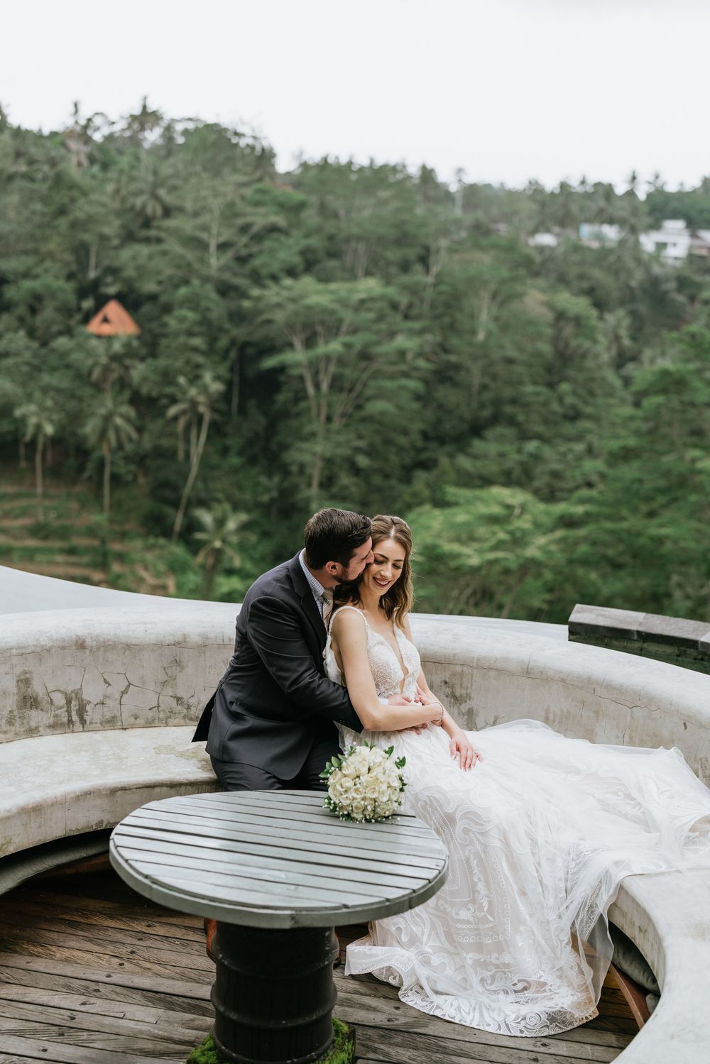 Newlyweds sharing intimate moments on a balcony with tropical landscape views.
