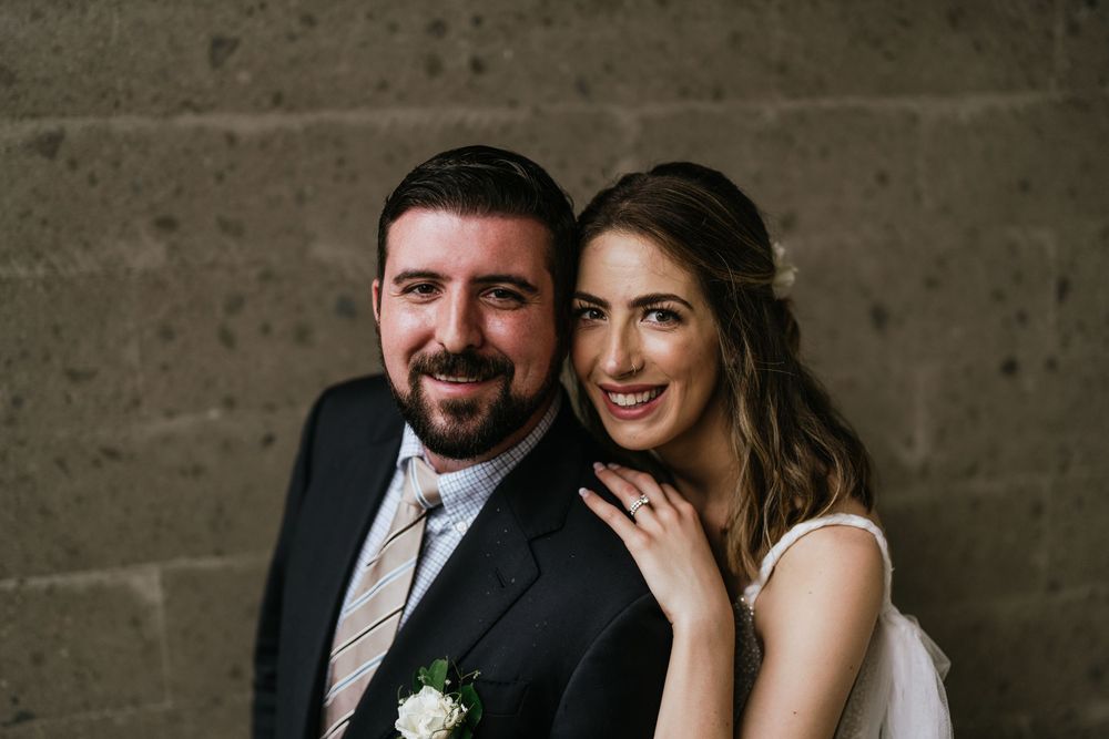 Romantic wedding portraits taken against a rustic concrete wall background.