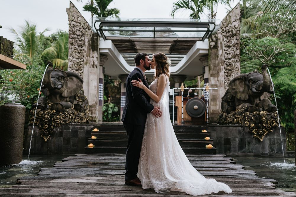 Wedding ceremony setup at a tropical venue with stone pillars and palm trees.