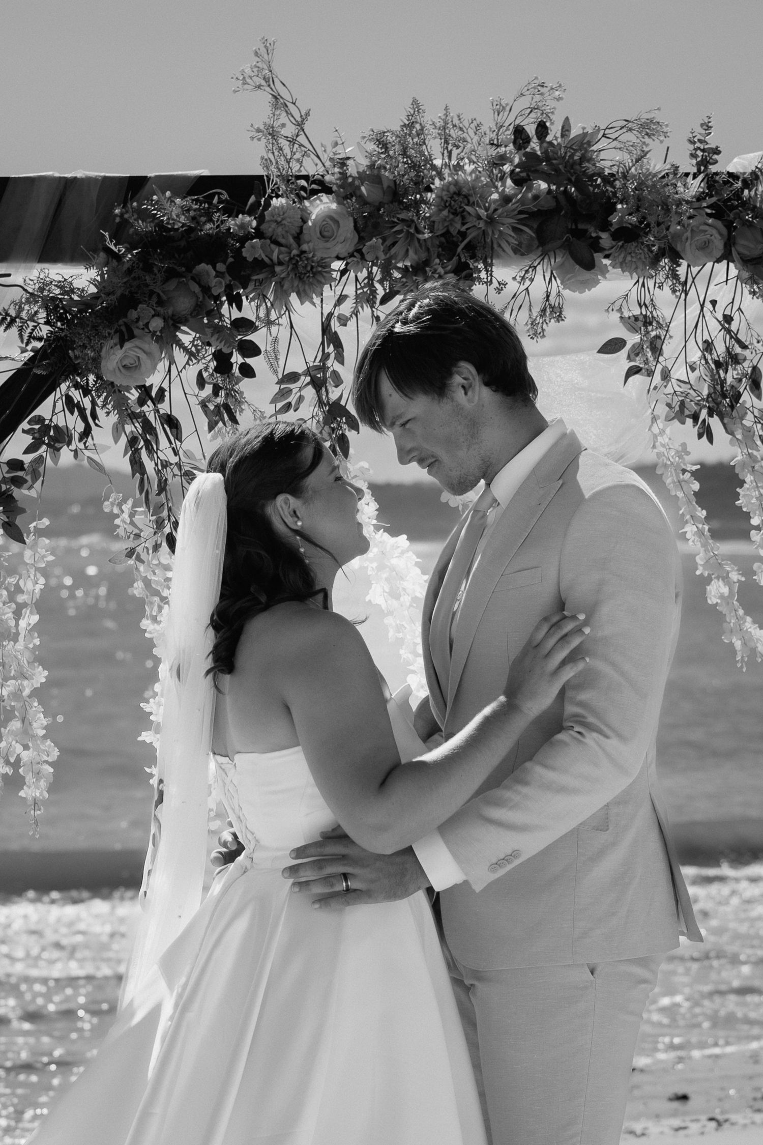 A romantic black and white photo sequence shows a couple embracing and kissing during an outdoor wedding ceremony.