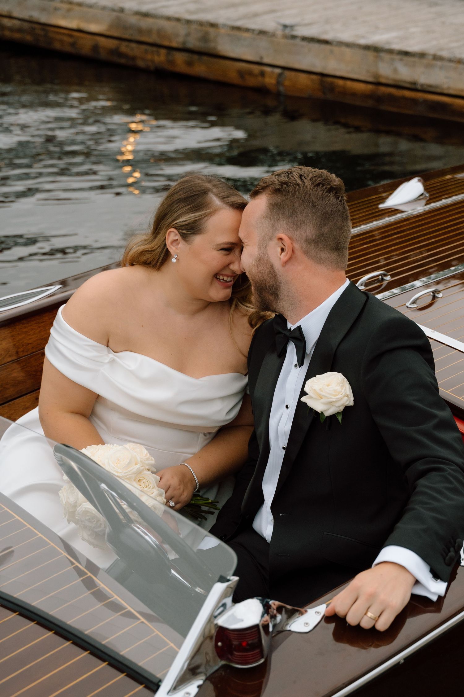 A couple shares an intimate moment on a wooden boat deck during their wedding celebration.