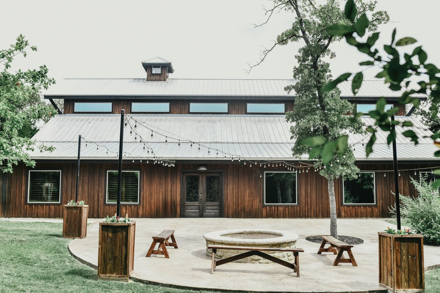 Romantic wooden benches surround a firepit on the outdoor reception and cocktail patio at whispering oaks wedding venue