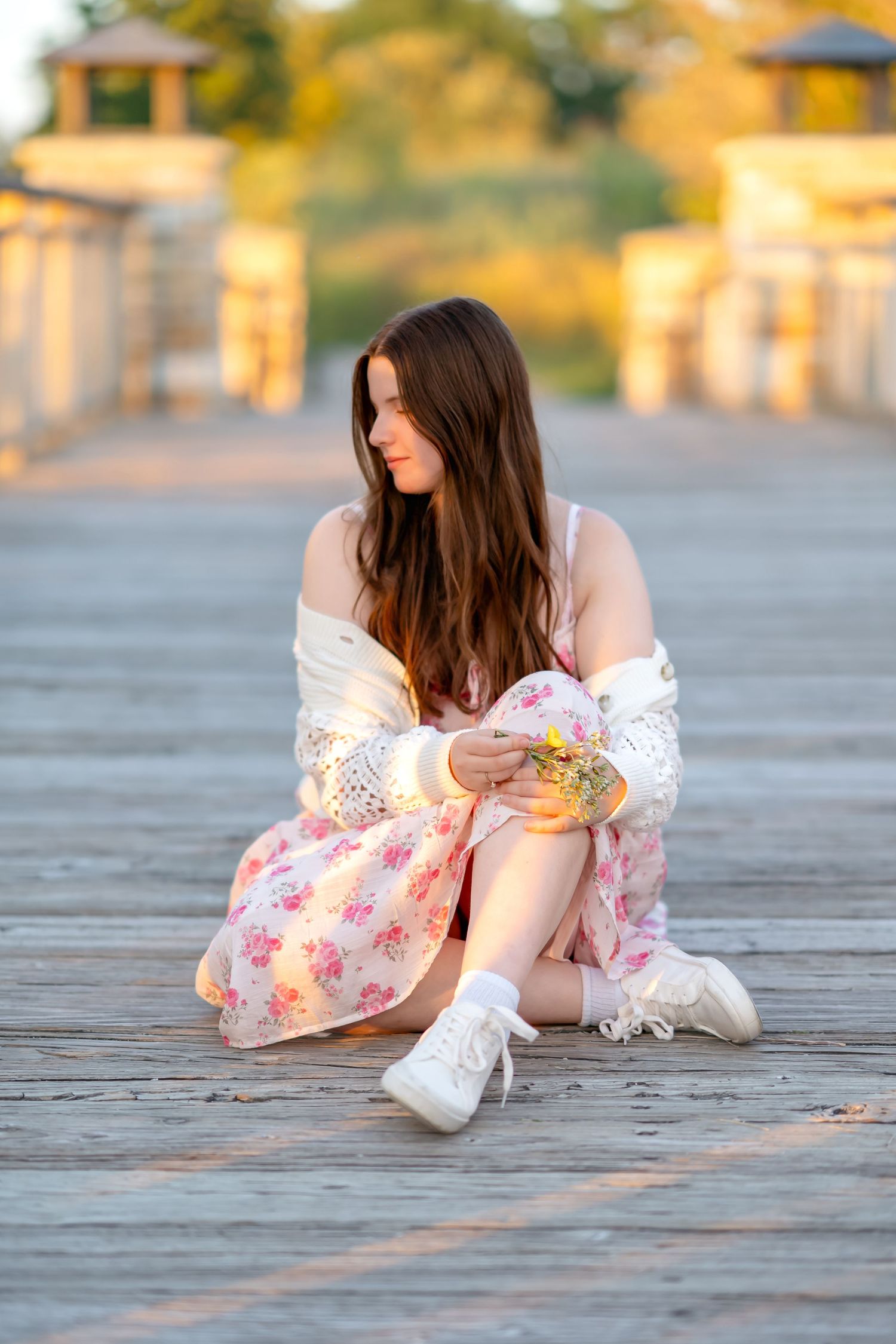 Artistic lifestyle poses on wooden deck wearing vintage-inspired floral dress during golden hour photoshoot.