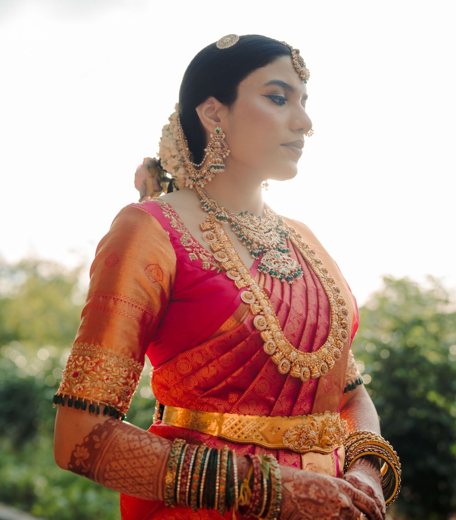 Ornate bridal jewelry and red silk saree details in natural lighting.