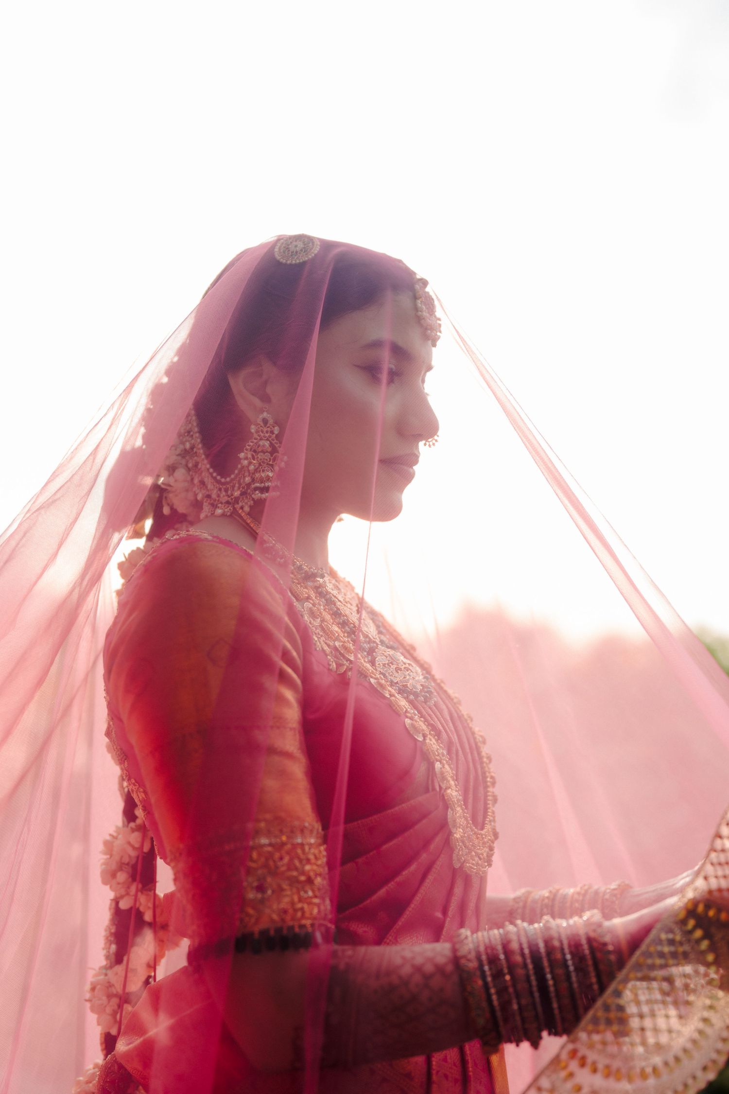 Artistic bridal portraits with soft pink veil creating ethereal lighting effects.