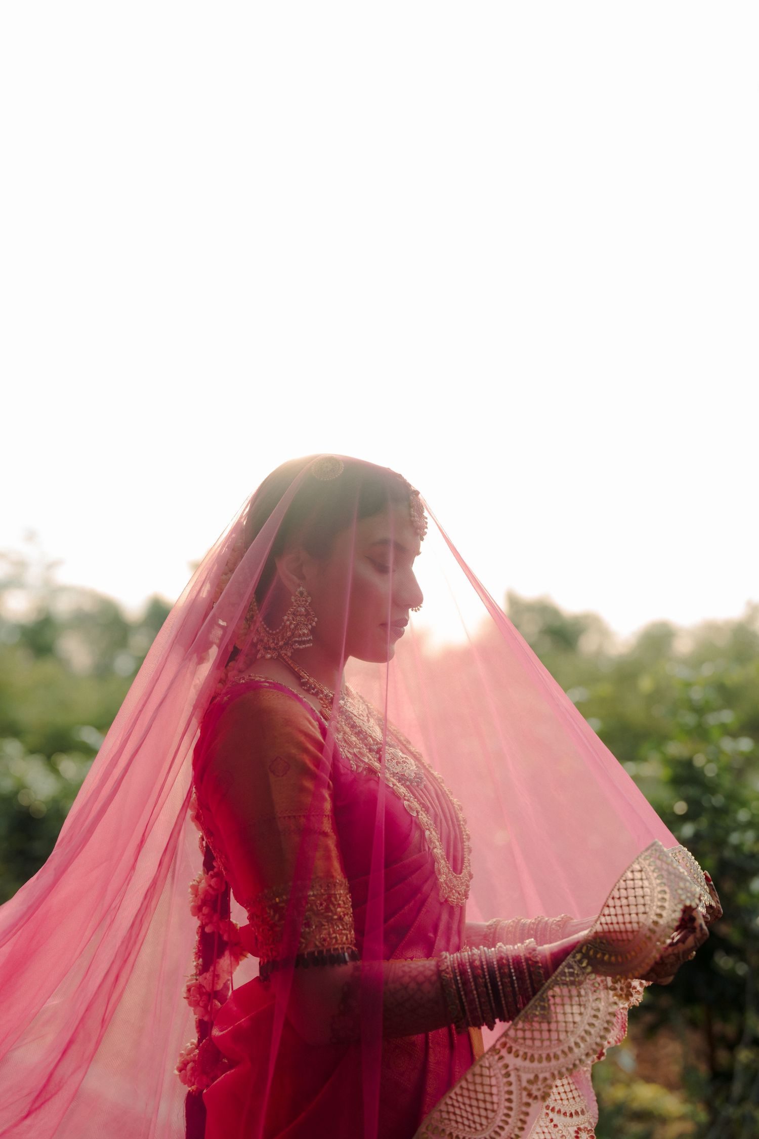 Ethereal bridal portrait with flowing pink veil in golden hour lighting.