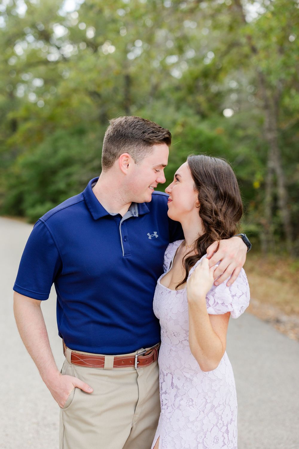 A couple in navy and white outfits share romantic moments outdoors at a scenic photo session.