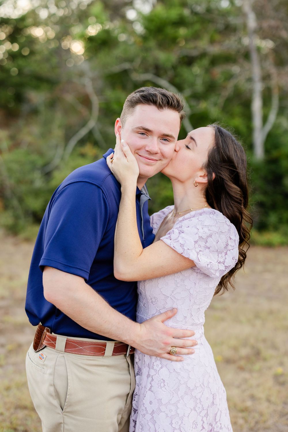 A couple shares a tender moment in an outdoor setting wearing coordinated white and navy blue outfits.