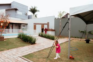 Two figures playing in a modern backyard space with stone pathways and palm trees near a white building exterior.