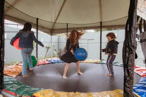 People enjoy turning and spinning while standing on a circular platform inside a colorful tent structure.