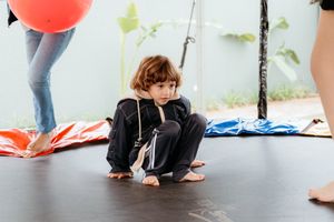 Children enjoy crawling under a row of chairs in a creative physical activity game during indoor playtime.