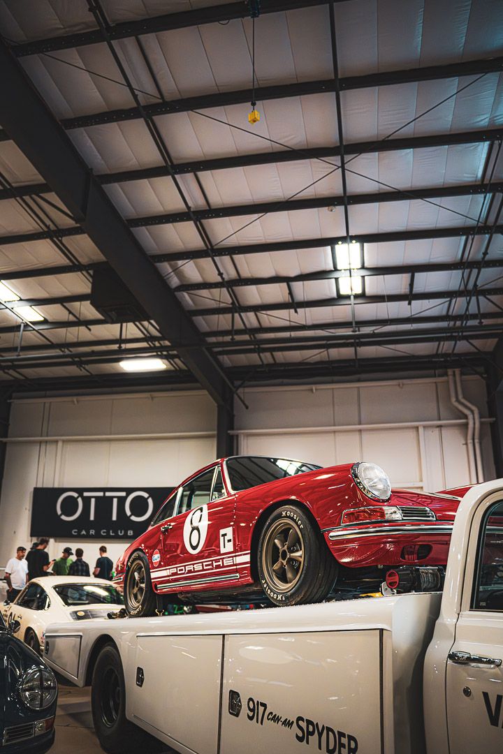 Classic red vintage race car displayed on platform in warehouse showroom with Otto branding.