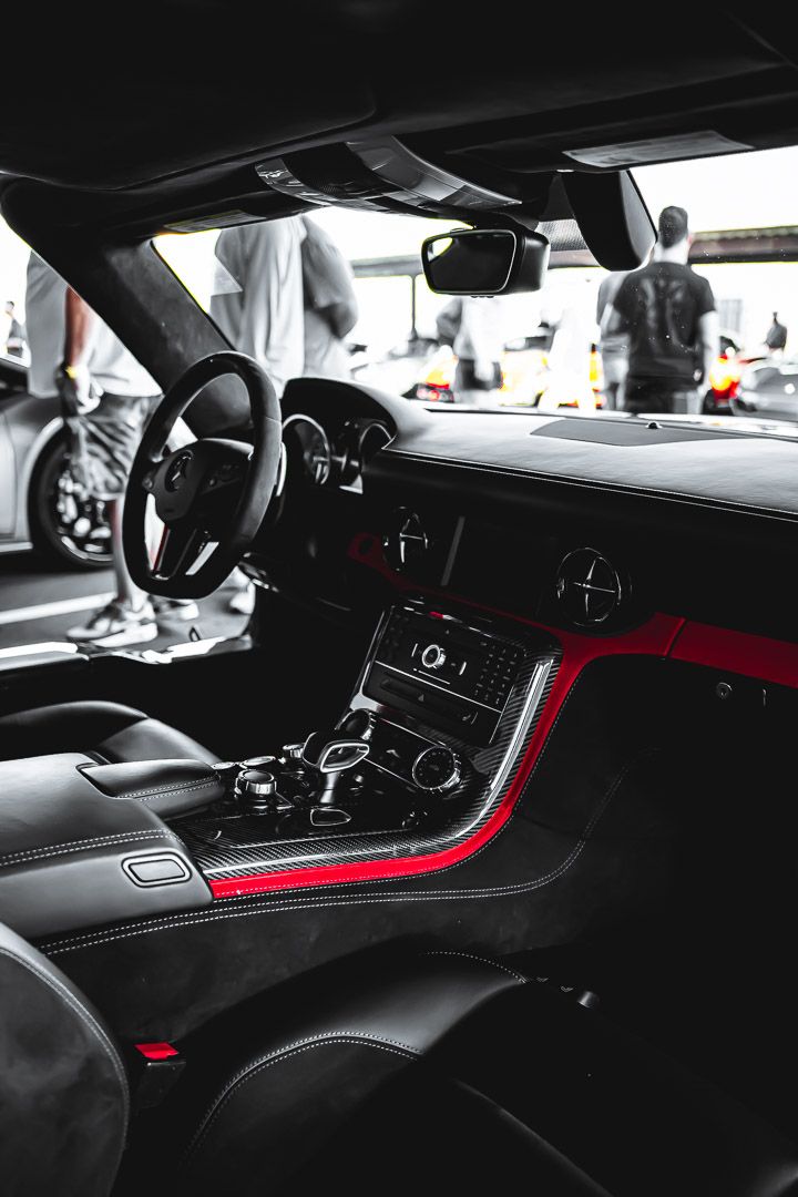 Luxury car interior featuring black leather seats with red accents and modern dashboard controls.