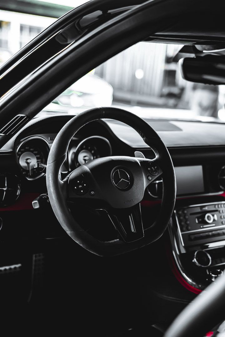 Interior dashboard views of a Mercedes-Benz showing the steering wheel and gauges in black and white.