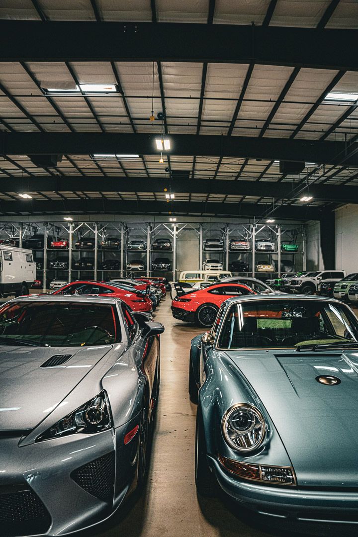 Modern sports cars including Porsches and luxury vehicles displayed in a well-lit indoor dealership facility.