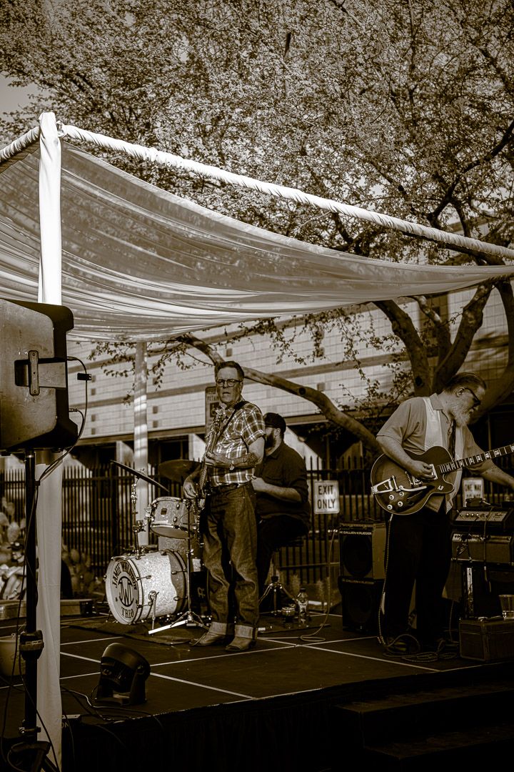 Outdoor event space with white canopy decorations and trees in sepia tone photography.