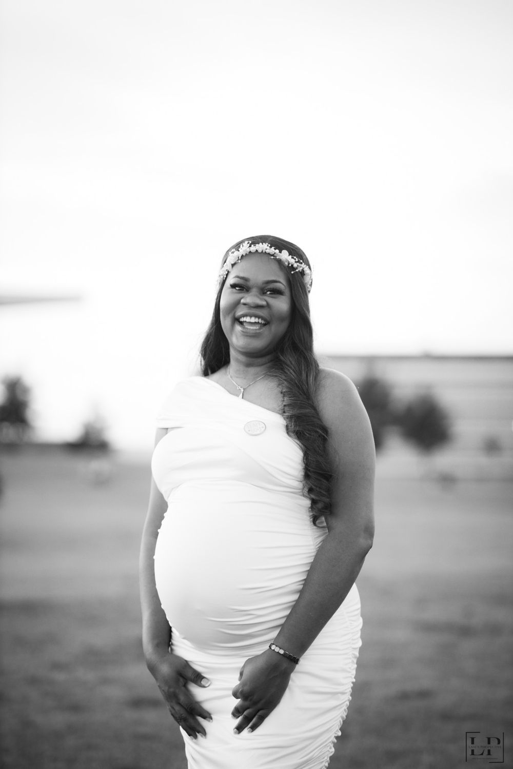Black and white maternity photos showing a pregnant figure in a white dress against a simple background.