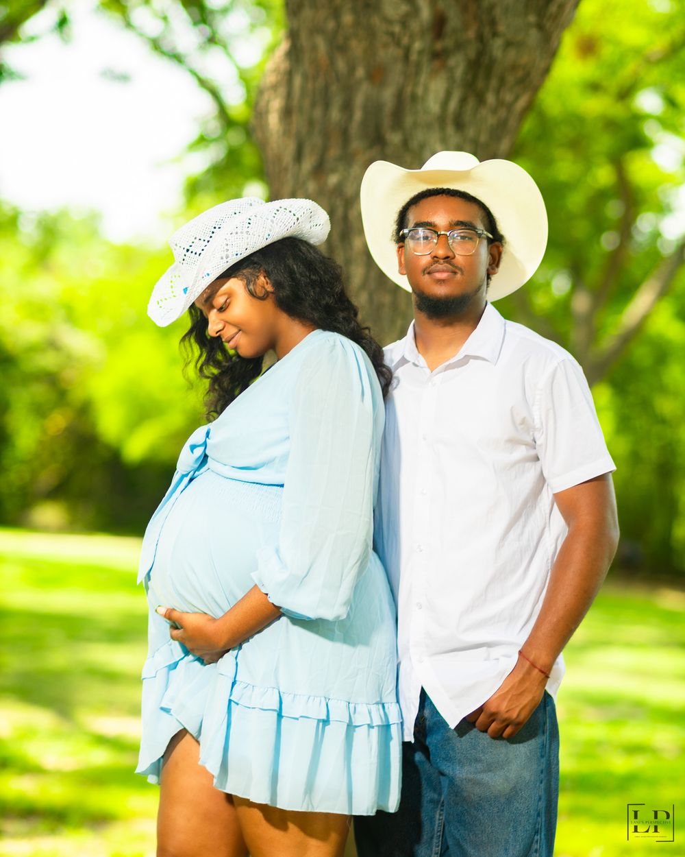 Casual outdoor photoshoot in park setting with light blue dress and white cowboy hats.