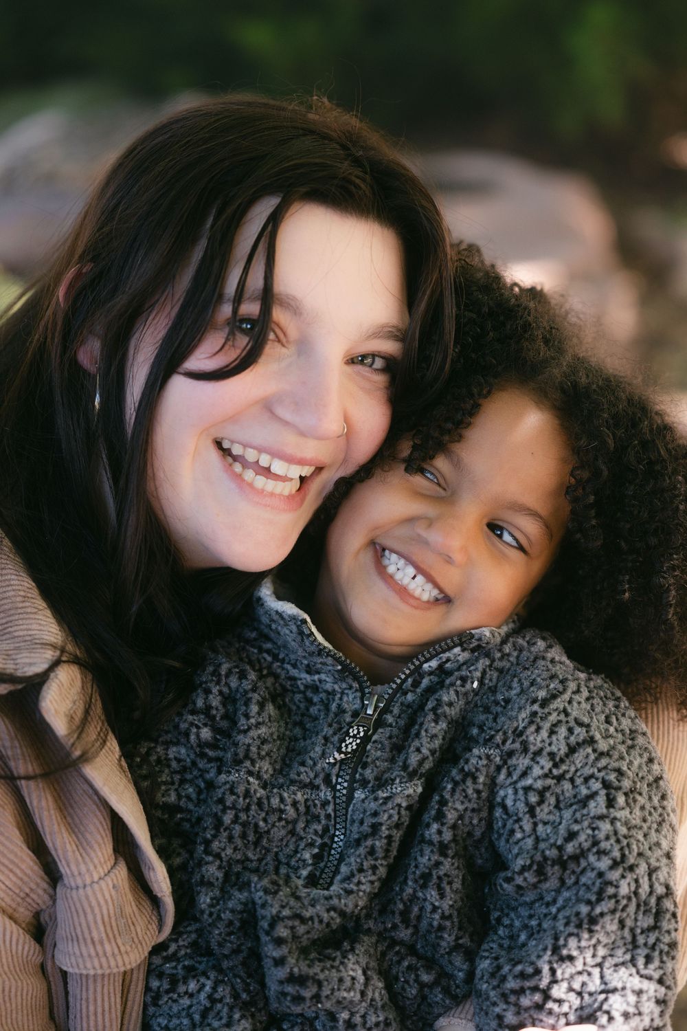Two friends sharing a close moment together while wearing cozy winter sweaters and scarves.