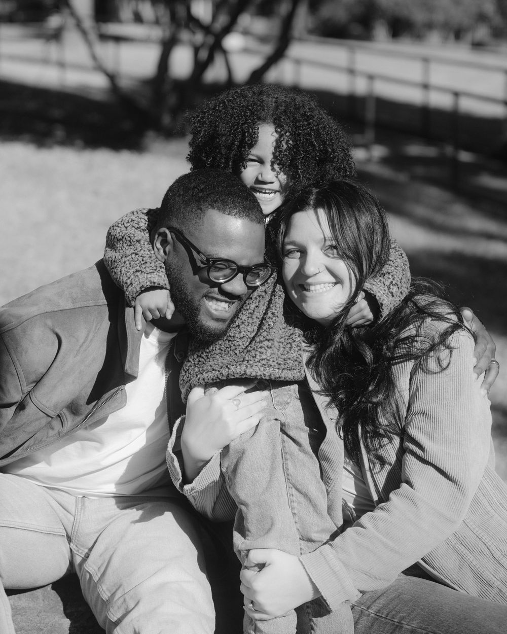 A romantic black and white photo series showing a couple embracing and laughing together outdoors.