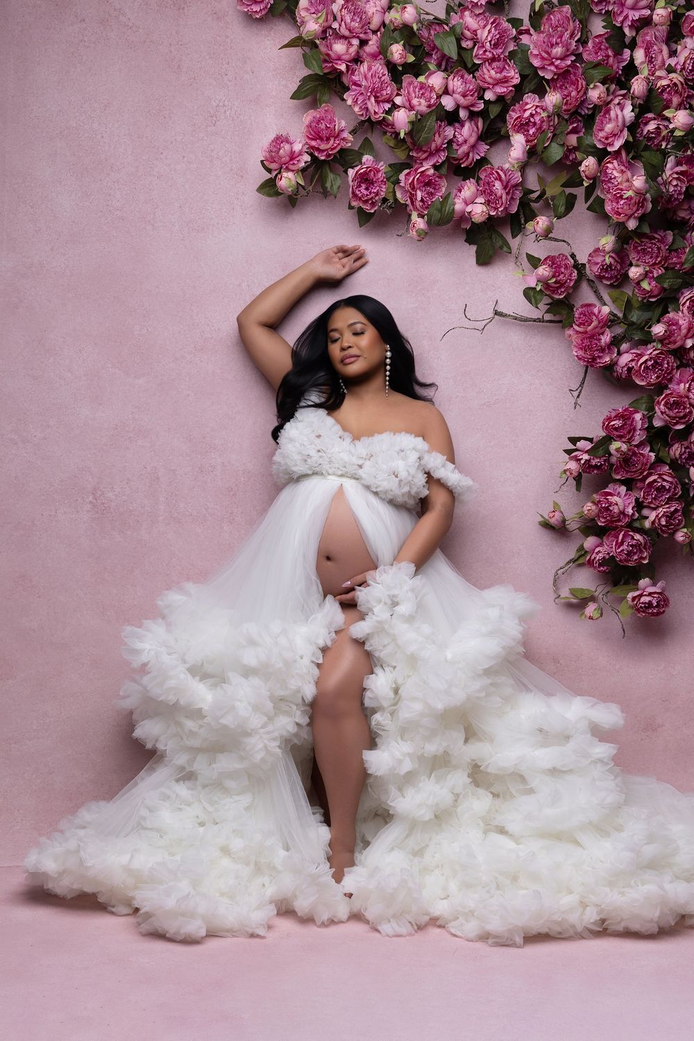 Glamour photo series featuring flowing white tulle gown against pink wall with cascading pink roses.