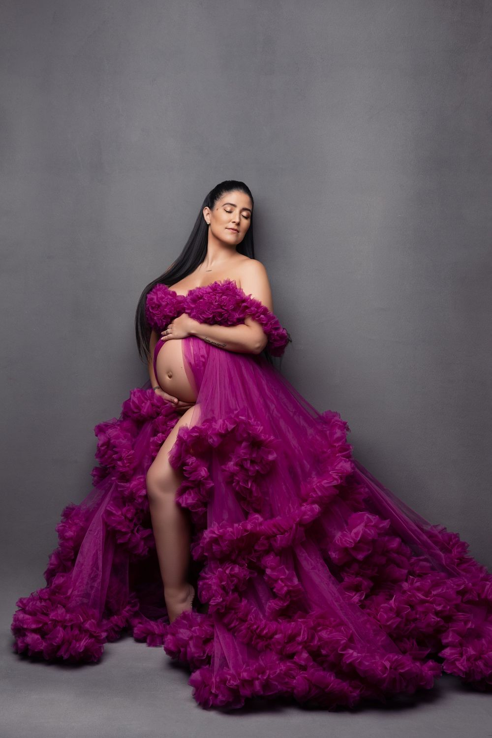 A dramatic fashion portrait series featuring a flowing magenta tulle gown against a gray studio backdrop.