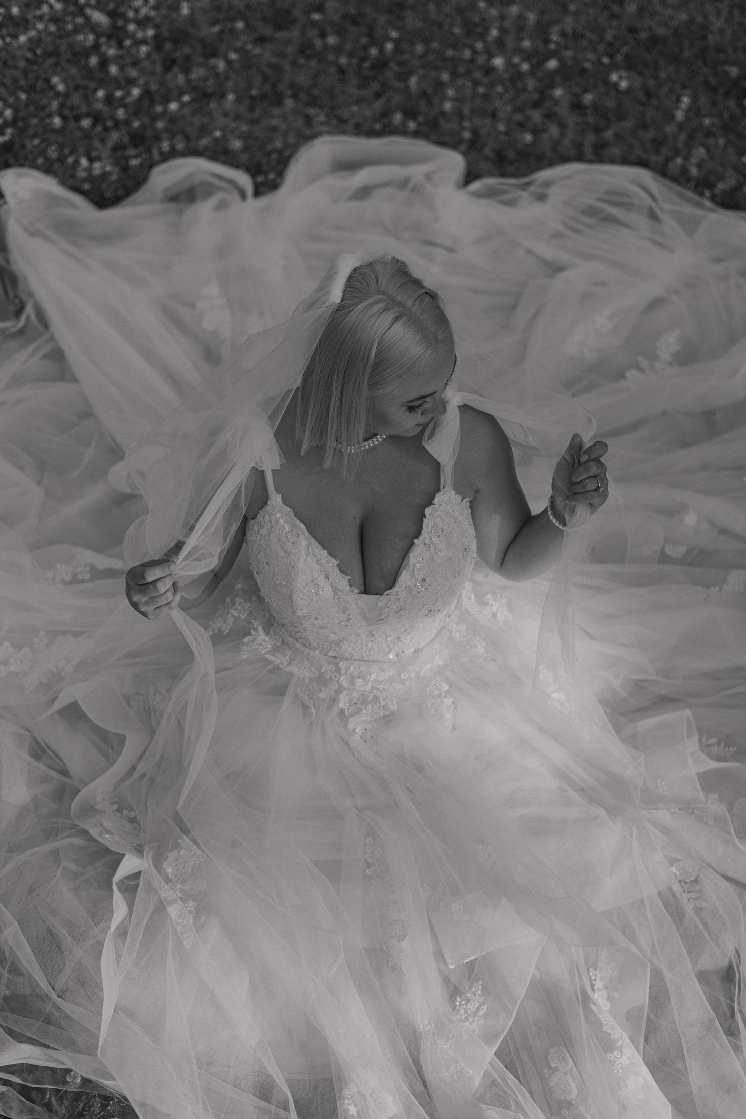 Artistic black and white portrait of bride in flowing tulle wedding dress.