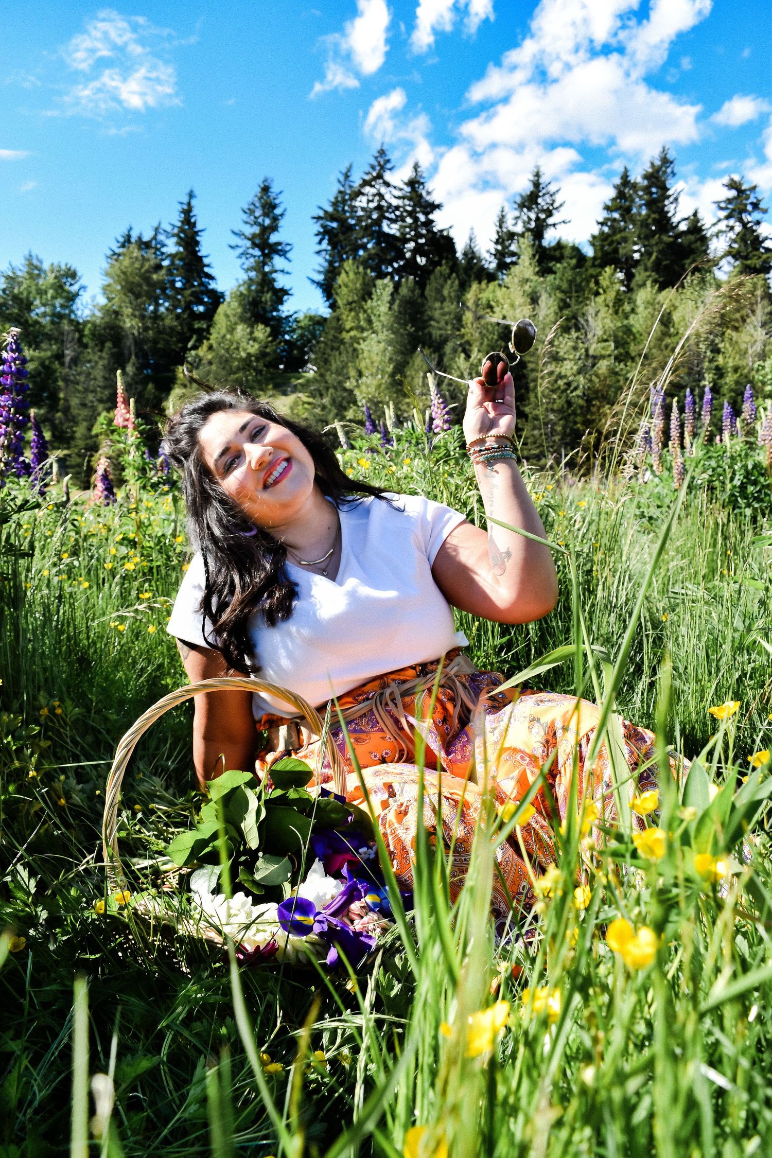 Woman in a bright floral dress posing in a wildflower meadow under blue skies and summer sun, full of color and joy Kent, WA. Lupine Session