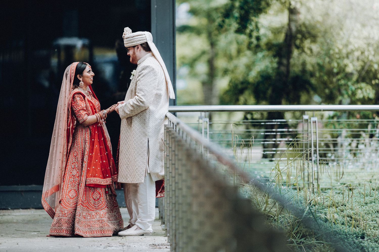 Traditional South Asian wedding ceremony with couple in ornate red and cream cultural attire.