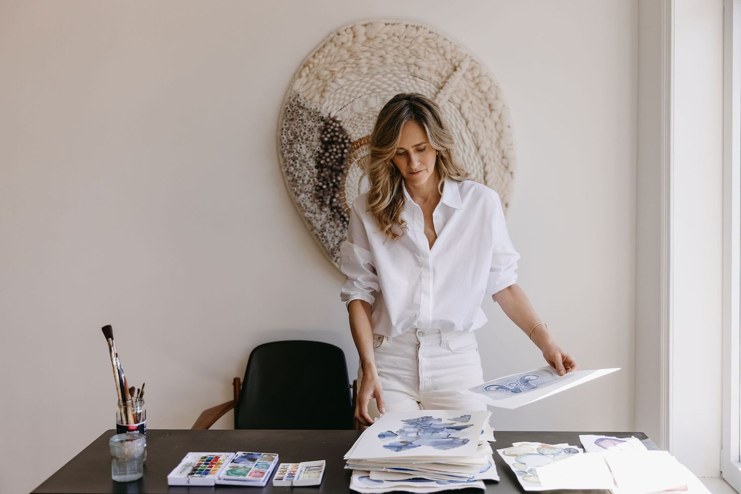 Modern workspace setup with white shirt and papers against decorative circular wall art.