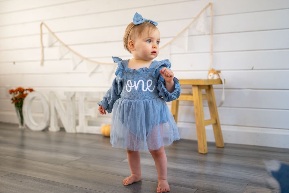 Blue and white tulle dress with 'one' text for first birthday celebration. Cake smash