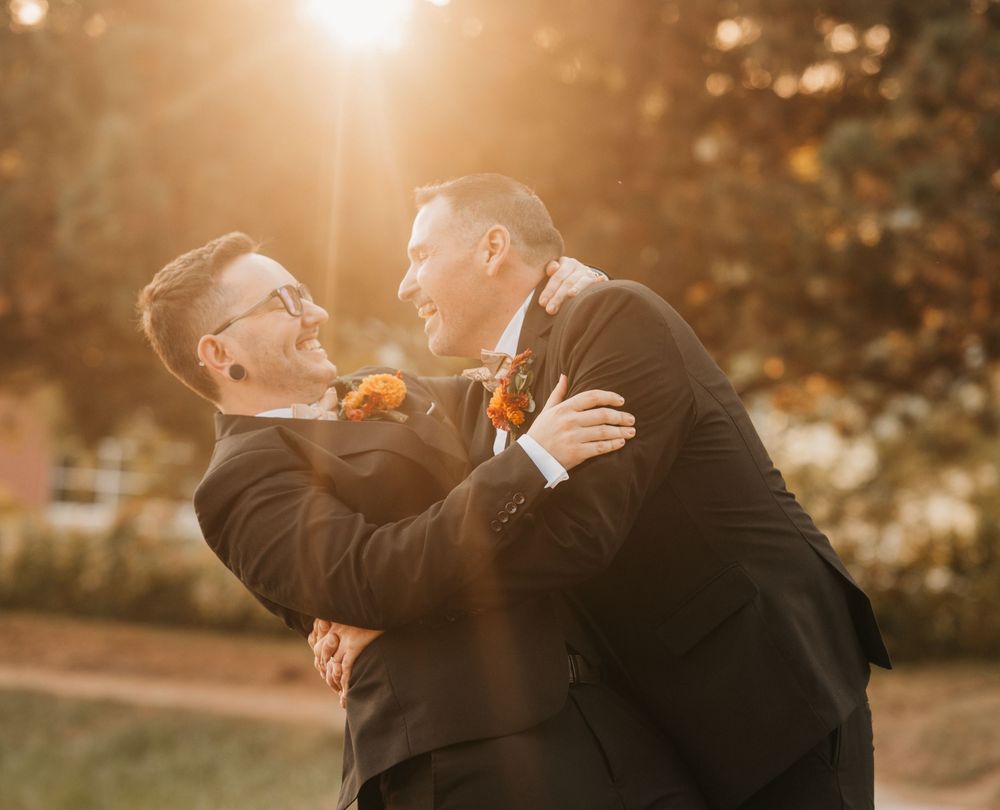 A couple shares an intimate moment at sunset in a garden with warm golden lighting and autumn foliage.