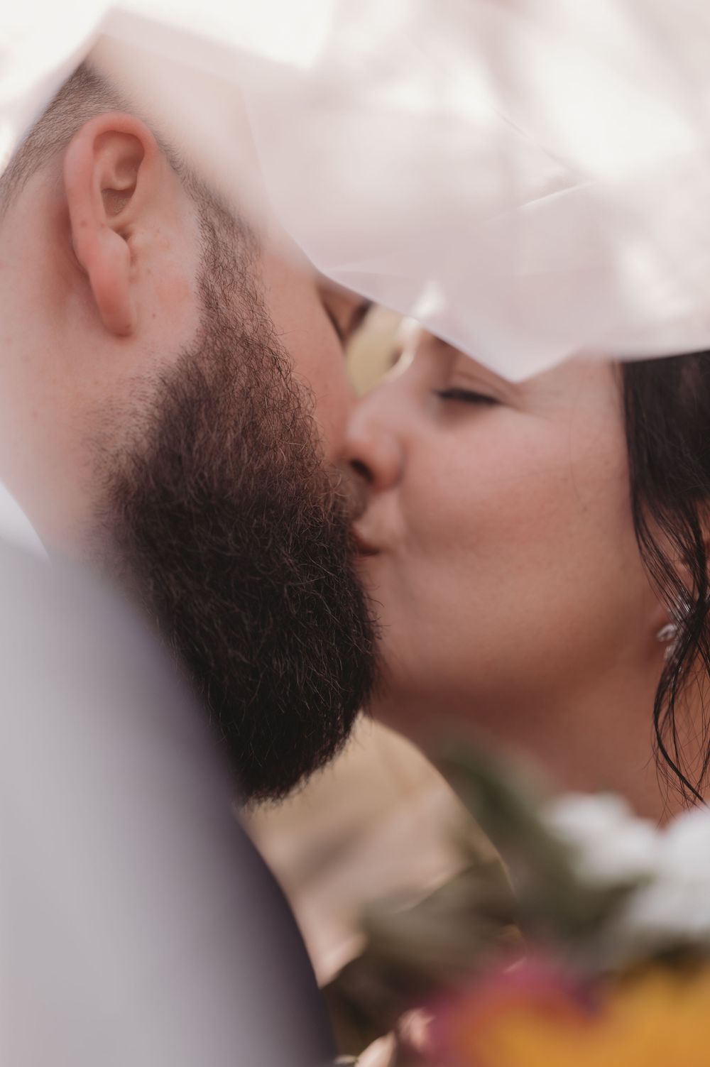 A romantic close-up shot shows a tender kiss between a couple against a soft blurred background.