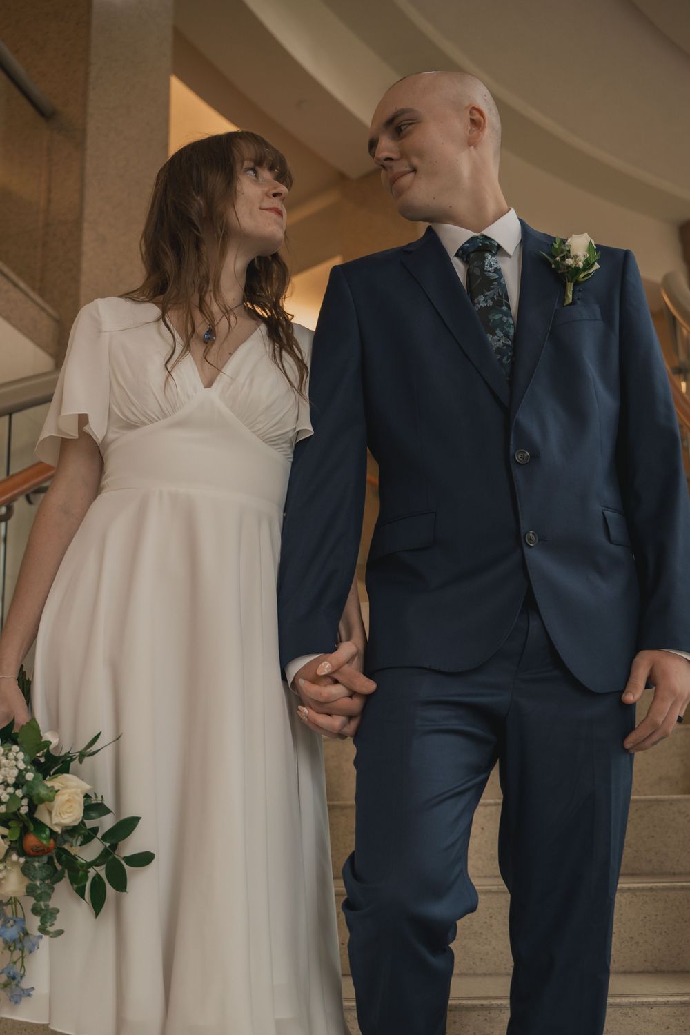 A bride and groom share intimate moments in a series of candid wedding photos against a stone column backdrop.