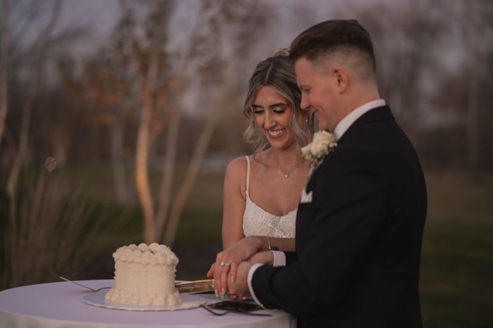 A romantic wedding couple shares an intimate moment during their outdoor reception at sunset.