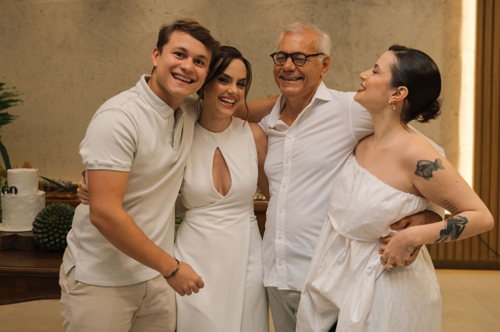 A group wearing white outfits pose together in a casual indoor setting.