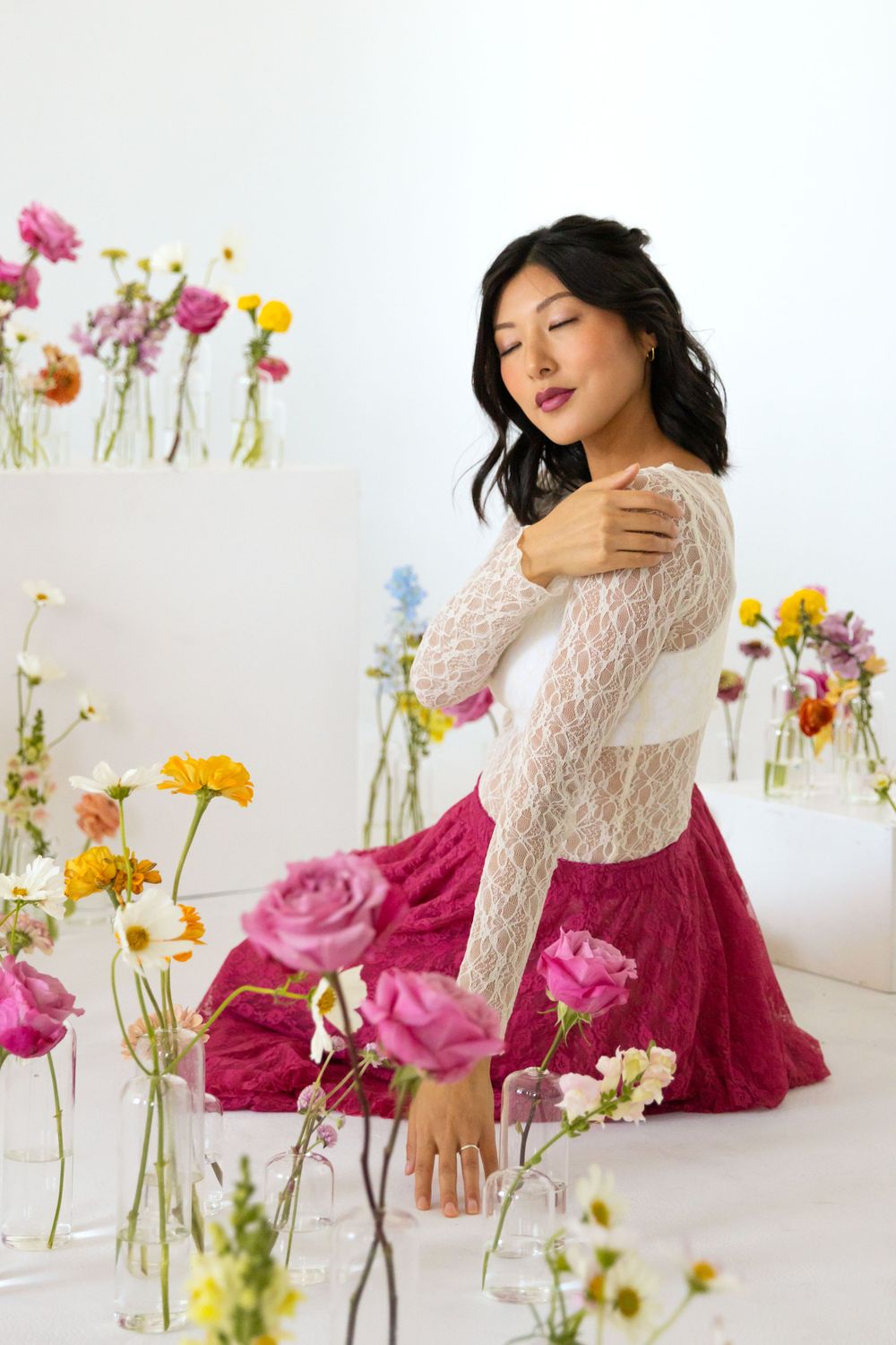 A creative portrait of a woman with flowers in vases in the foreground and bold colors.