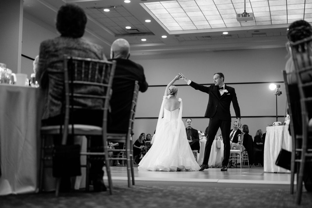 A black and white photo capturing a dancing moment at a wedding reception.