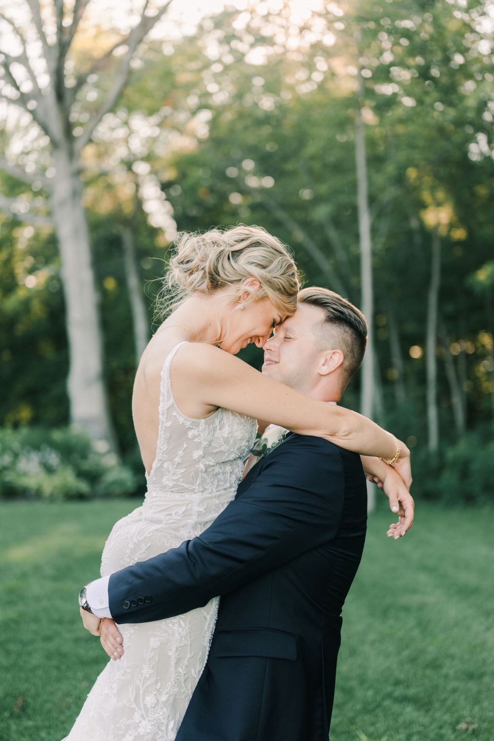 Newlyweds share an intimate embrace on their wedding day in a sunlit garden setting.