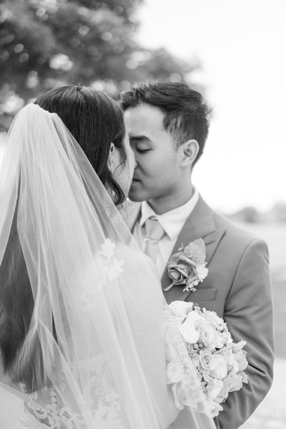 Romantic wedding portrait with white flowers and flowing veil.