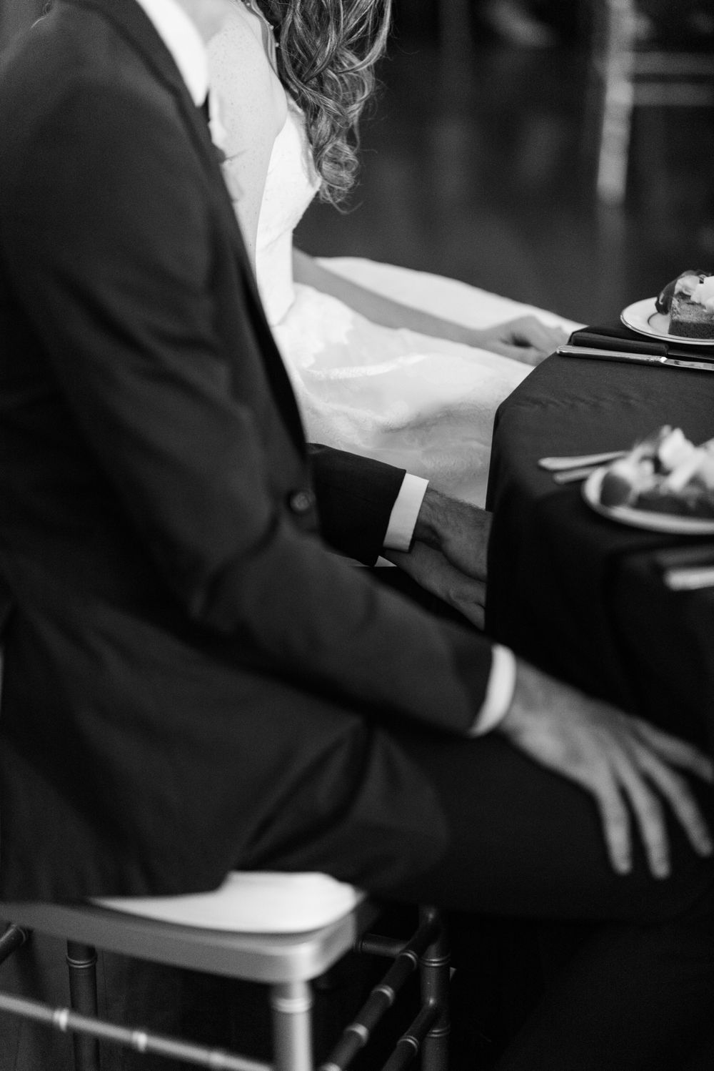Close-up of hands playing piano keys in black and white.