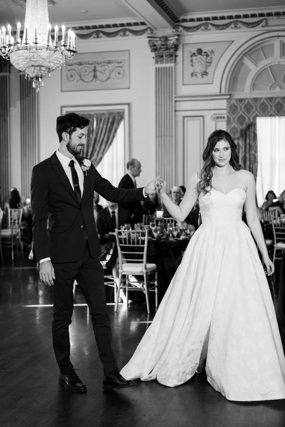 Wedding couple dancing in an ornate ballroom with elegant architectural details.