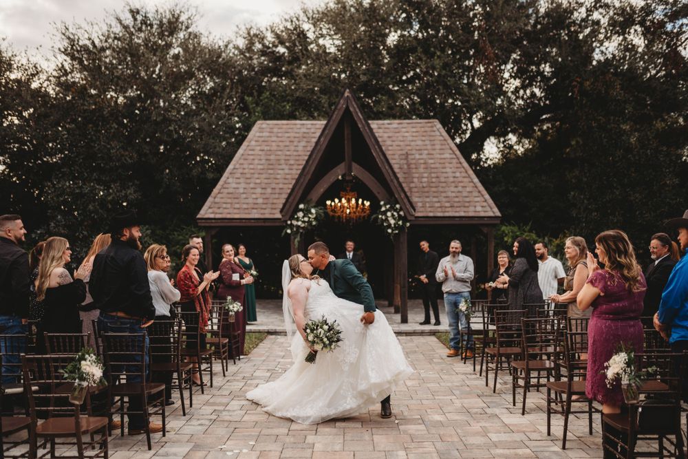 Wedding couple dancing in aisle between rows of chairs at outdoor chapel ceremony.